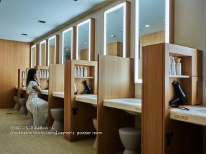 a woman standing in a bathroom with sinks and mirrors at First Cabin Nishi Umeda in Osaka