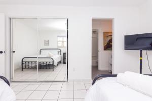 Cette chambre blanche dispose d'un miroir et d'un lit. dans l'établissement Two Bedroom Apartment - with Parking & Balcony - Heart of Wynwood, à Miami