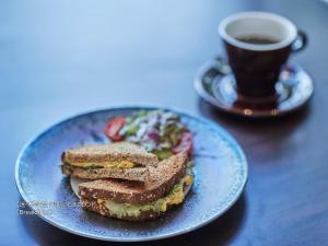 a sandwich on a blue plate next to a cup of coffee at First Cabin Nishi Umeda in Osaka
