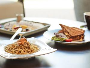 a table with two plates of pasta and a sandwich at First Cabin Nishi Umeda in Osaka