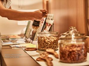 a woman is holding a bottle of nuts in jars on a table at First Cabin Nishi Umeda in Osaka