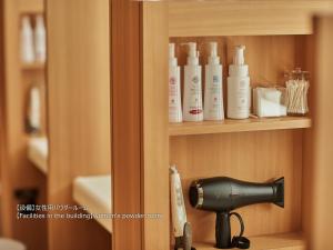 a shelf with a hair dryer and other products on it at First Cabin Nishi Umeda in Osaka