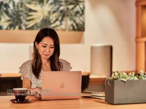 a woman sitting at a table using a laptop computer at First Cabin Nishi Umeda in Osaka