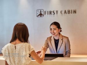 a woman shaking hands with a woman at a table at First Cabin Nishi Umeda in Osaka