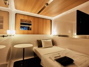 a small room with a bed and a table at First Cabin Nishi Umeda in Osaka