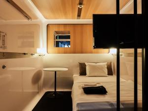 a small bedroom with a bed and a table at First Cabin Nishi Umeda in Osaka
