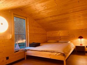 a bed in a log cabin with a window at Dom Blisko Natury Boszkowo Letnisko Dom B in Boszkowo-Letnisko