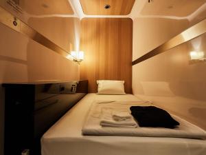 a small bed in a room with at First Cabin Nishi Umeda in Osaka