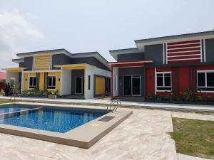 ein Haus mit einem Pool vor einem Haus in der Unterkunft Kedawang Village Langkawi in Pantai Cenang
