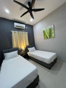 two beds in a room with a ceiling fan at Kedawang Village Langkawi in Pantai Cenang