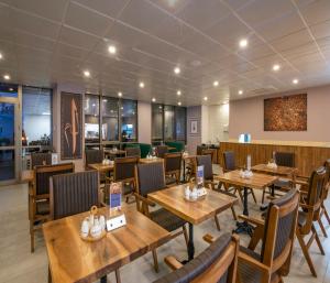 comedor con mesas y sillas de madera en MAA Hotel and Suites - Hurlingham, Nairobi, en Nairobi