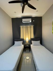 2 Betten in einem Zimmer mit Deckenventilator in der Unterkunft Kedawang Village Langkawi in Pantai Cenang