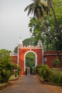 an archway leading to a red building with a palm tree at Sawantwadi Palace Boutique Art Hotel in Sawantwadi