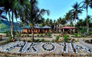 a resort with a flower arrangement in front of a building at Akoya Beach Sunset Camp in El Nido