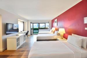 a hotel room with three beds and a flat screen tv at Grand China Bangkok in Bangkok