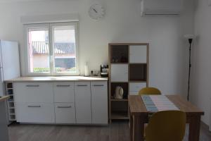 kuchnia z białymi szafkami, stołem i oknem w obiekcie Le Beau site by Beds83 w Fréjus