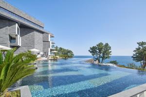 ソギポにあるJW Marriott Jeju Resort & Spaの海の見える建物の隣にあるスイミングプール