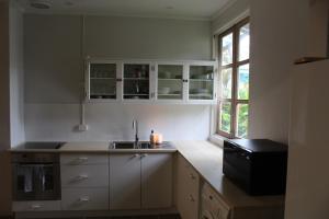 uma cozinha com armários brancos, um lavatório e uma janela em Rumah Biru em Flying Fish Cove