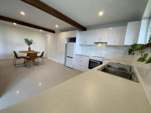 uma cozinha com armários brancos e uma mesa em Wave Cave Suite em Coffs Harbour