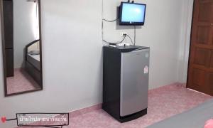 a small refrigerator in a room with a tv on a wall at Ban Rai Plai Na บ้านไร่ปลายนารีสอร์ท in Ban Mai Pho Thong