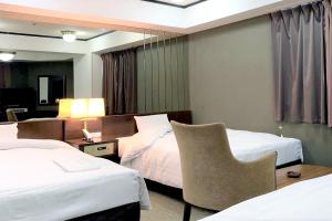 a hotel room with two beds and a chair at Ramada Encore by Wyndham Amagasaki in Amagasaki