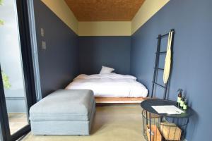 a bedroom with blue walls and a bed and a stool at THE CHIKURA UMI BASECAMP in Awa