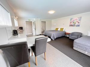 een kamer met 2 bedden en een tafel en stoelen bij Continental Motel in Whangarei