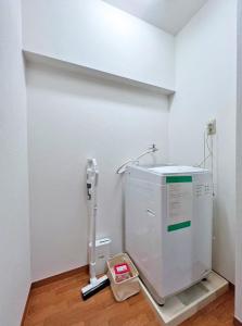 ein Zimmer mit einer Waschmaschine in der Ecke eines Zimmers in der Unterkunft 渋谷Eアドレス in Tokio