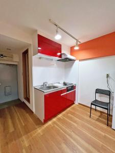 - une cuisine avec des placards rouges et un évier dans l'établissement 渋谷Eアドレス, à Tokyo