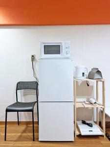 eine Mikrowelle auf einem Kühlschrank neben einem Stuhl in der Unterkunft 渋谷Eアドレス in Tokio