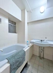 ein weißes Badezimmer mit einer Badewanne und einem Waschbecken in der Unterkunft 渋谷Eアドレス in Tokio