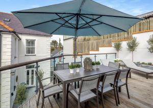 a patio table with a blue umbrella on a deck at Argraig in Abersoch