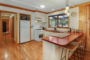 cocina con electrodomésticos blancos y suelo de madera en Woodland Rise en Mount Buller