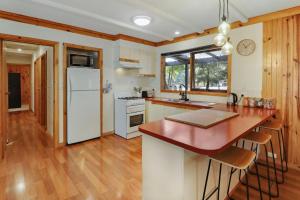 Una cocina con electrodomésticos blancos y suelo de madera. en Woodland Rise, en Mount Buller