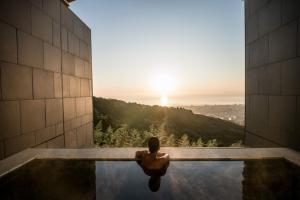 ANA InterContinental Beppu Resort & Spa, an IHG Hotel في بيبو: شخص جالس في مسبح مطل على غروب الشمس