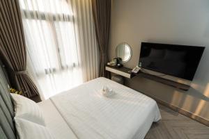 フーコックにあるLeeVi Homestay - Coffee - Milkteaのベッド1台、薄型テレビが備わるホテルルームです。