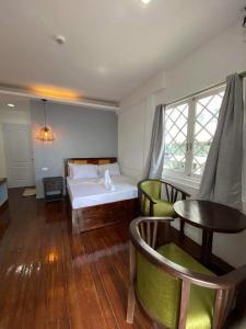 Dumaguete Seafront Hotel في دوماغيتي: غرفة نوم بسرير وطاولة وكراسي