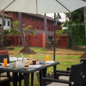 an umbrella over a table with food on it at Sawantwadi Palace Boutique Art Hotel in Sawantwadi