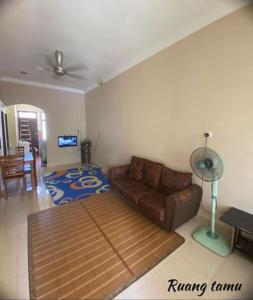 a living room with a couch and a fan at Sobey Laris Homestay AZANA in Pasir Mas