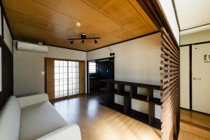 een woonkamer met een witte bank en houten plafonds bij 島のまくら in Kure