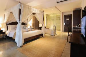 a bedroom with a canopy bed and a bath room at Visesa Ubud Resort in Ubud