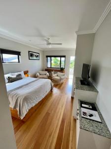 a bedroom with a bed and a television and a couch at Aabi's at Byron in Byron Bay