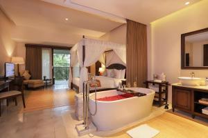 a bathroom with a bath tub and a bedroom at Visesa Ubud Resort in Ubud