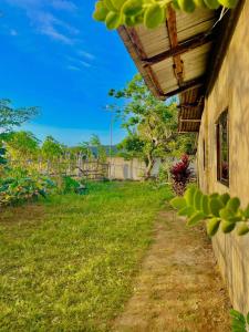 a house with a grass yard next to a building at TINA TRANSIENT HOME in Nasugbu