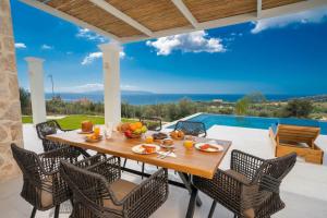 una mesa y sillas en un patio con vistas al océano en Natural Stone Villas Kefalonia en Trapezaki