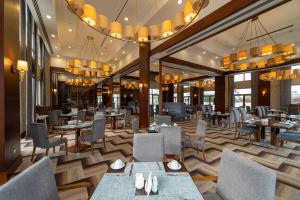 a restaurant with tables and chairs and chandeliers at Wellborn Luxury Hotel in Kocaeli