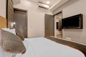 1 dormitorio con 1 cama blanca y TV de pantalla plana en Townhouse Siri Residency, en Bangalore
