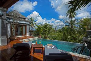 a swimming pool with a table and chairs next to a villa at Visesa Ubud Resort in Ubud