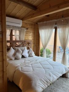 Schlafzimmer mit einem großen Bett mit weißer Bettwäsche und Vorhängen in der Unterkunft شاليةالخفجي in Al Khafji