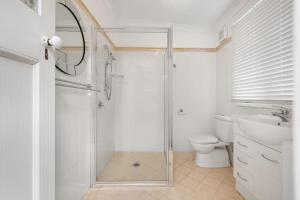 a white bathroom with a shower and a toilet at Currawong in Blackheath